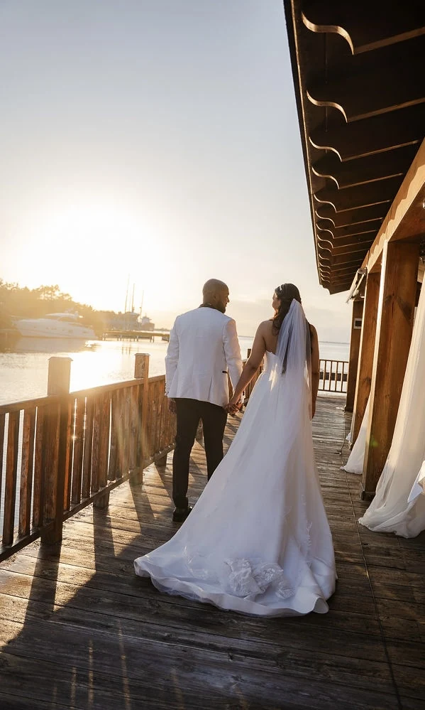Newlyweds walking together beside the water at sunset